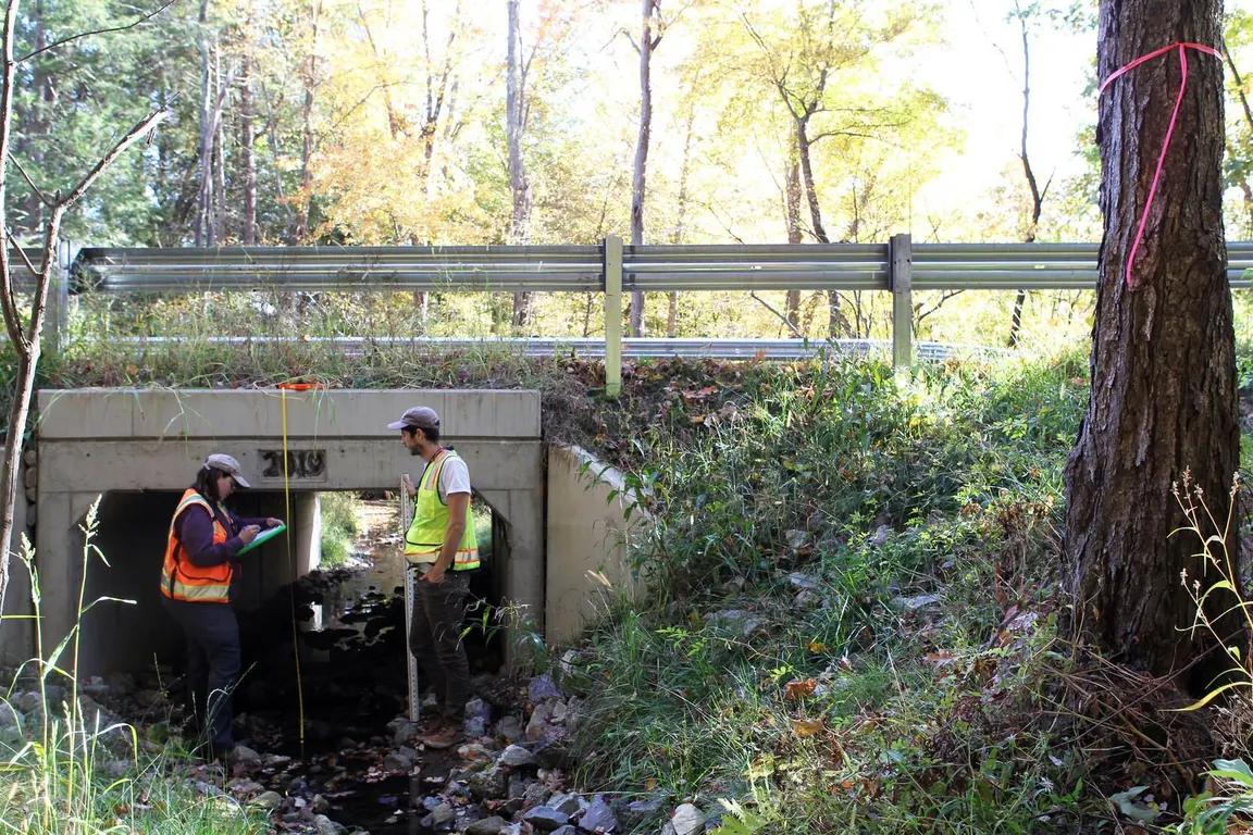 Box culvert crossing under a rural road with crew at work