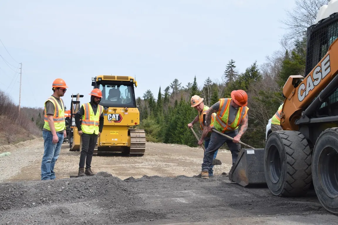 Crew installing a culvert under a gravel roadway