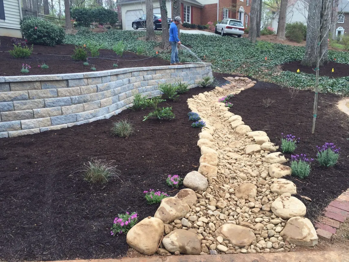 River-rock drainage swale through a landscaped yard
