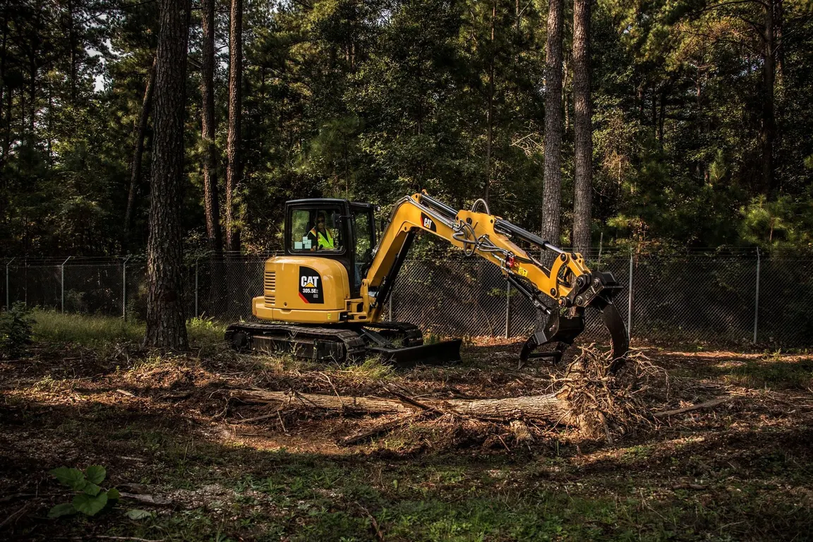 Excavator clearing stumps and brush from a wooded lot