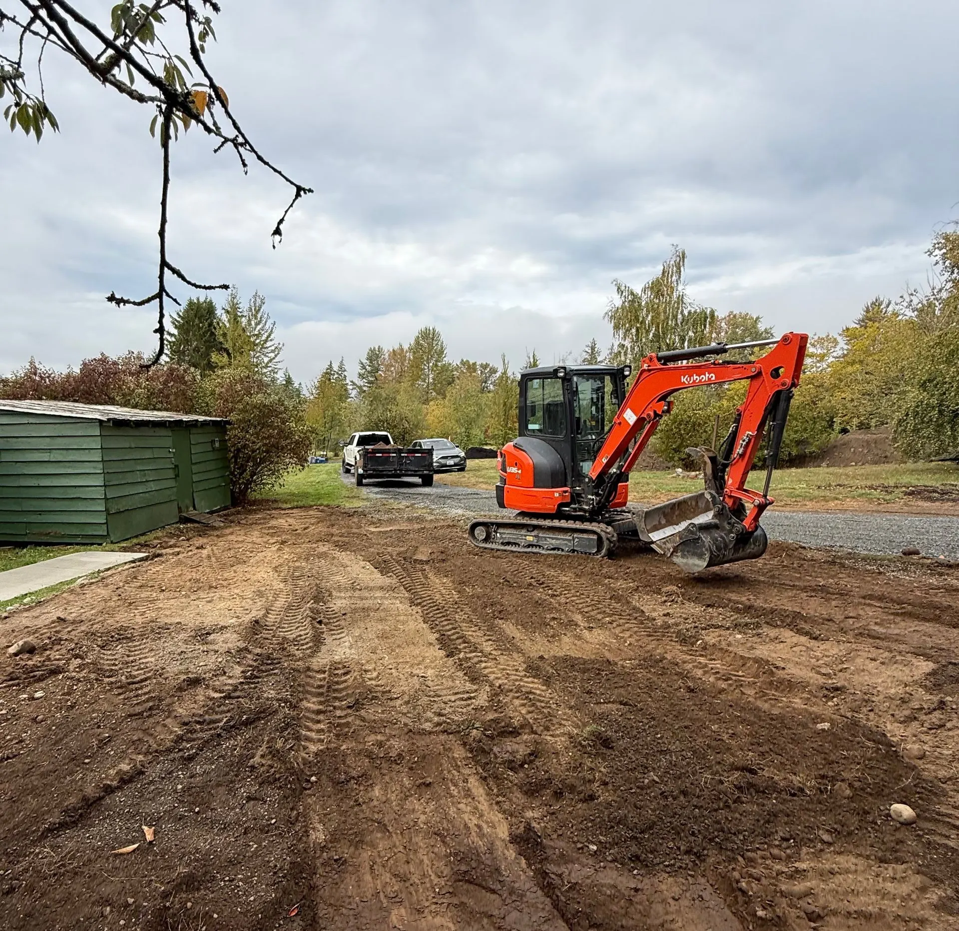 Compact excavator working on a freshly graded dirt lane