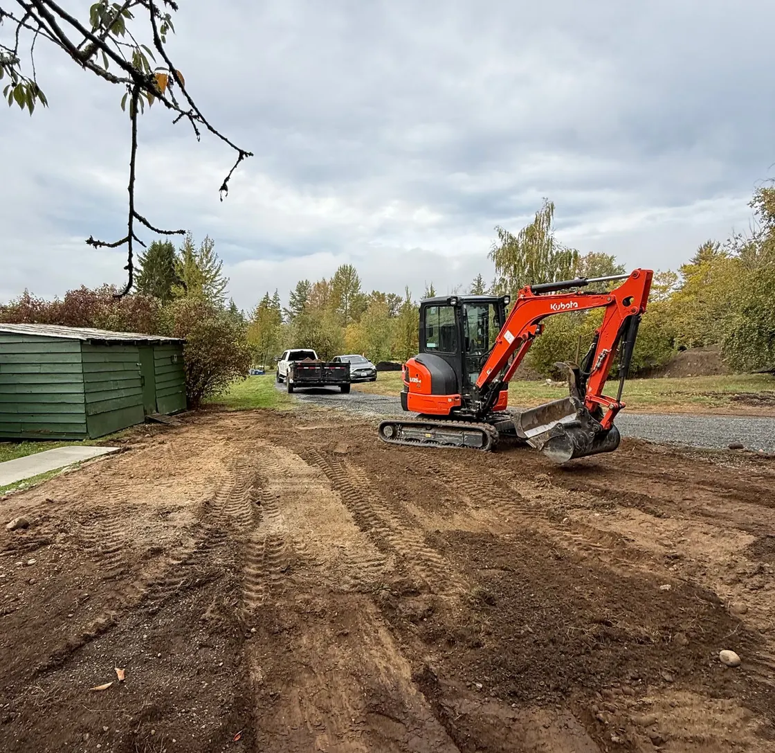Compact excavator working on a freshly graded dirt lane