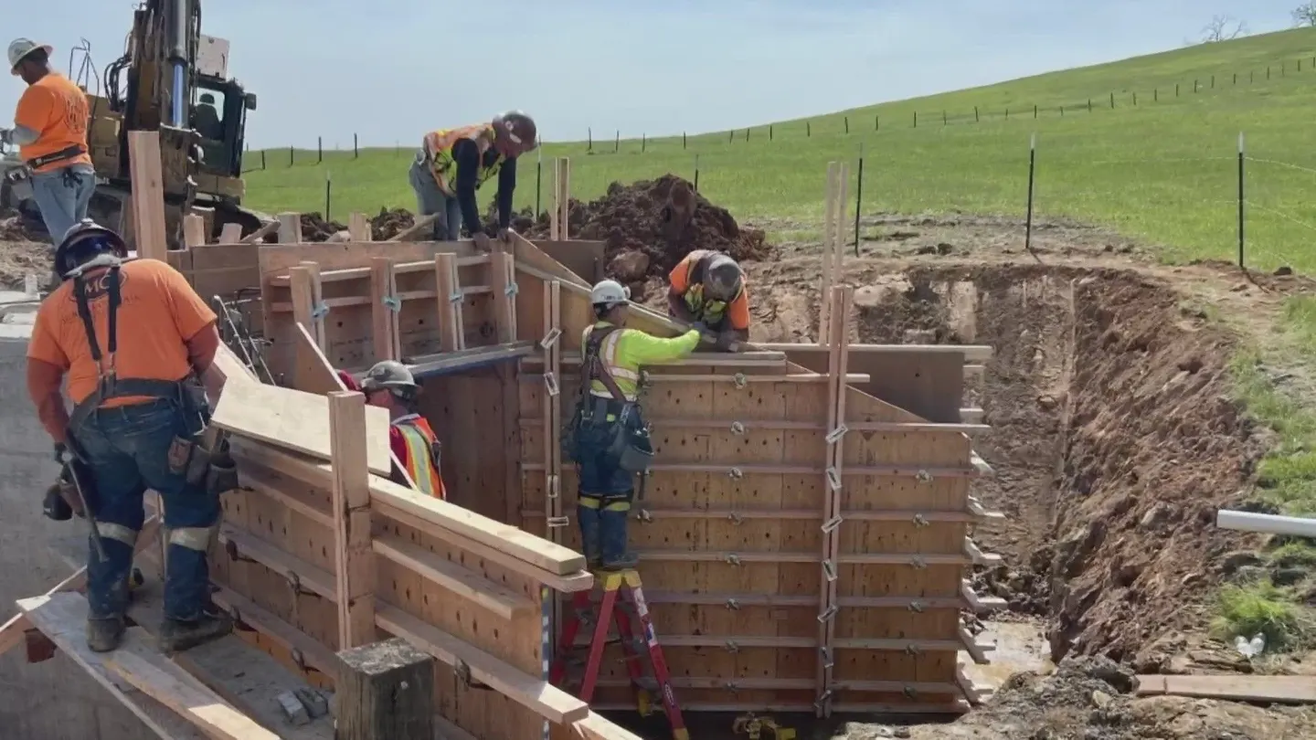 Crew forming a concrete culvert headwall in an open trench