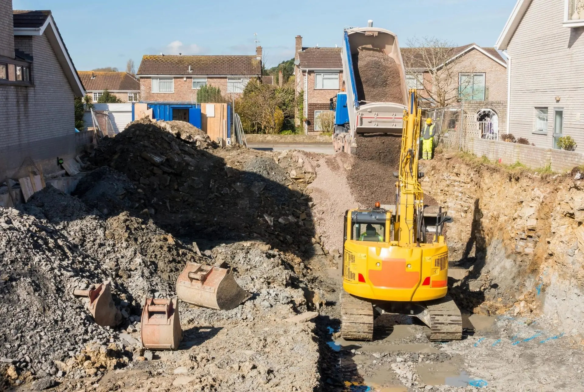 Excavator and dump truck removing debris at a demolition site