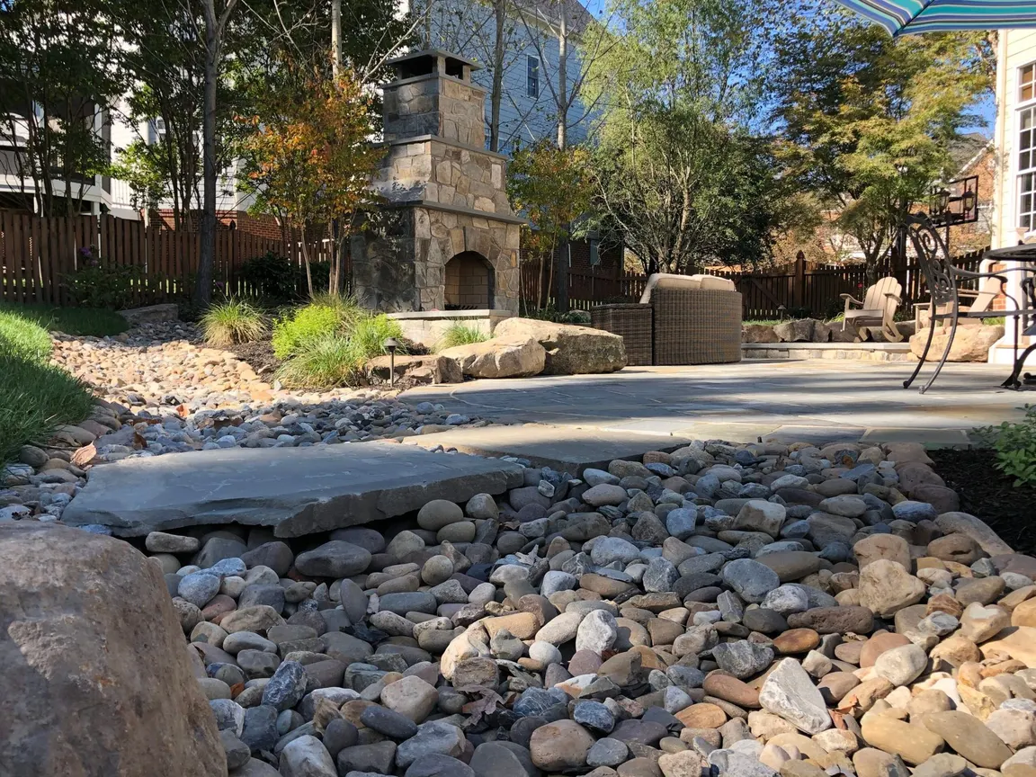 River-rock drainage bed around a backyard patio