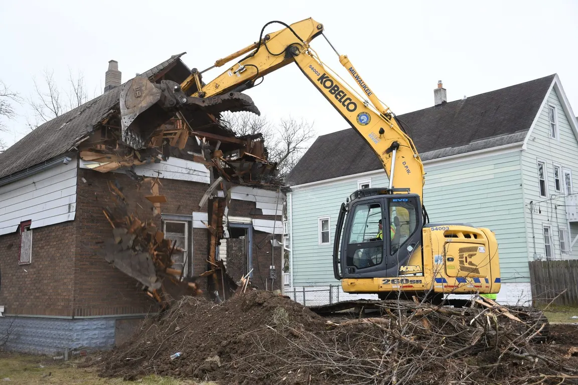 Excavator pulling down the wall of a house during demolition