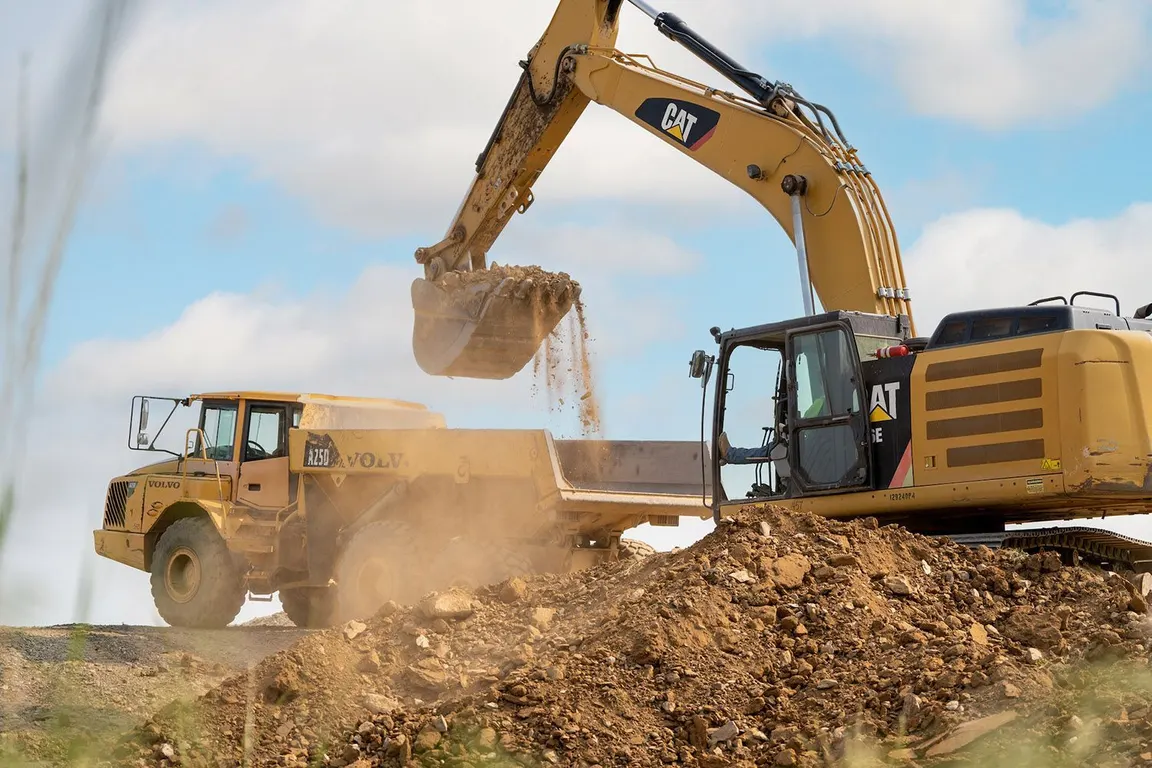Excavator loading debris into an articulated dump truck