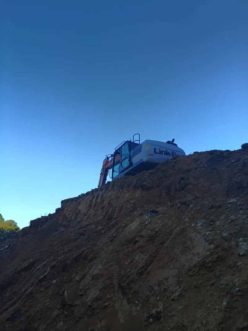 Excavator working on top of a large dirt stockpile