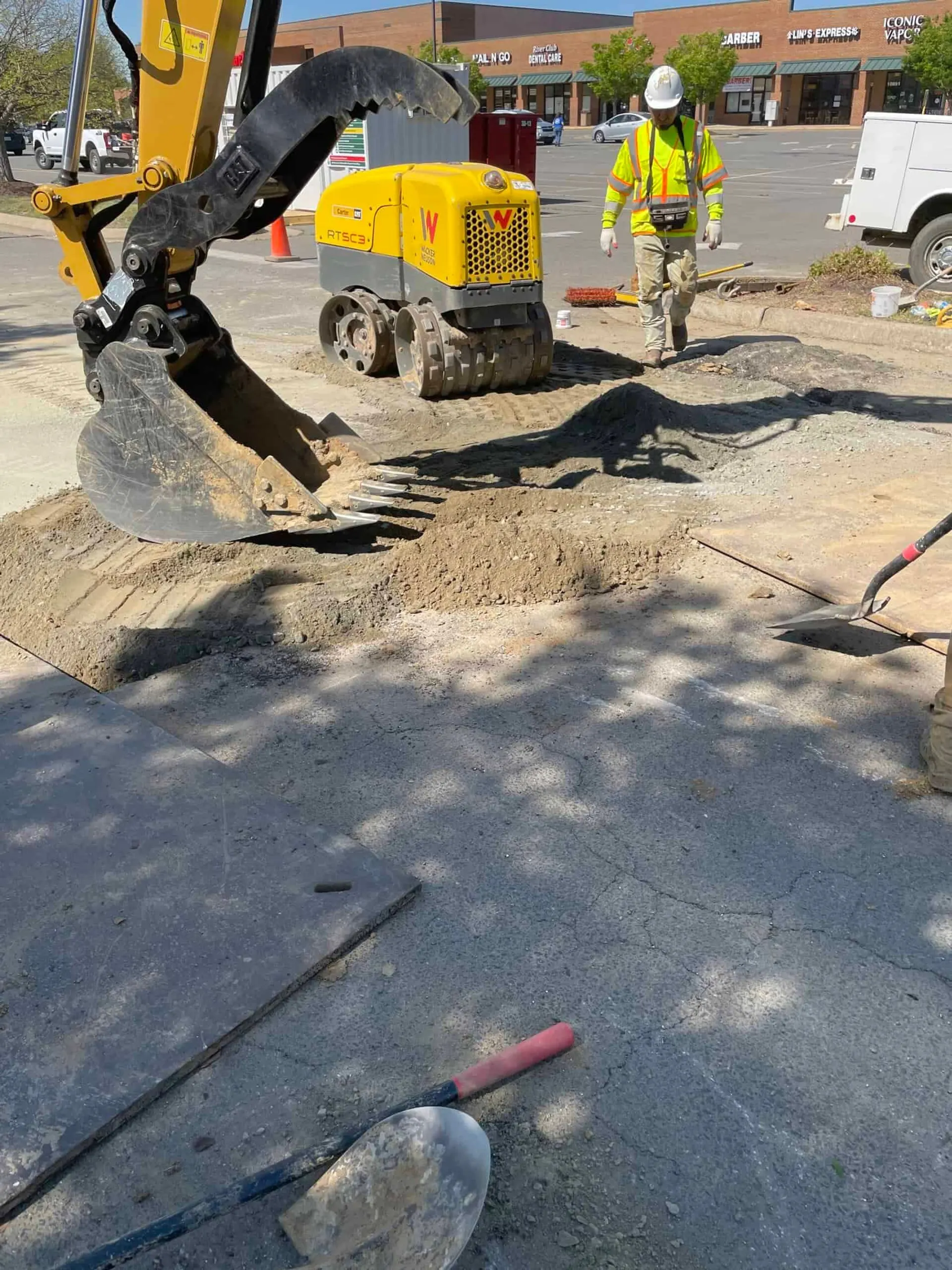Compact excavator breaking up asphalt with a hydraulic hammer