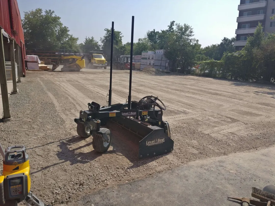 Laser-guided grading box leveling gravel on a job site