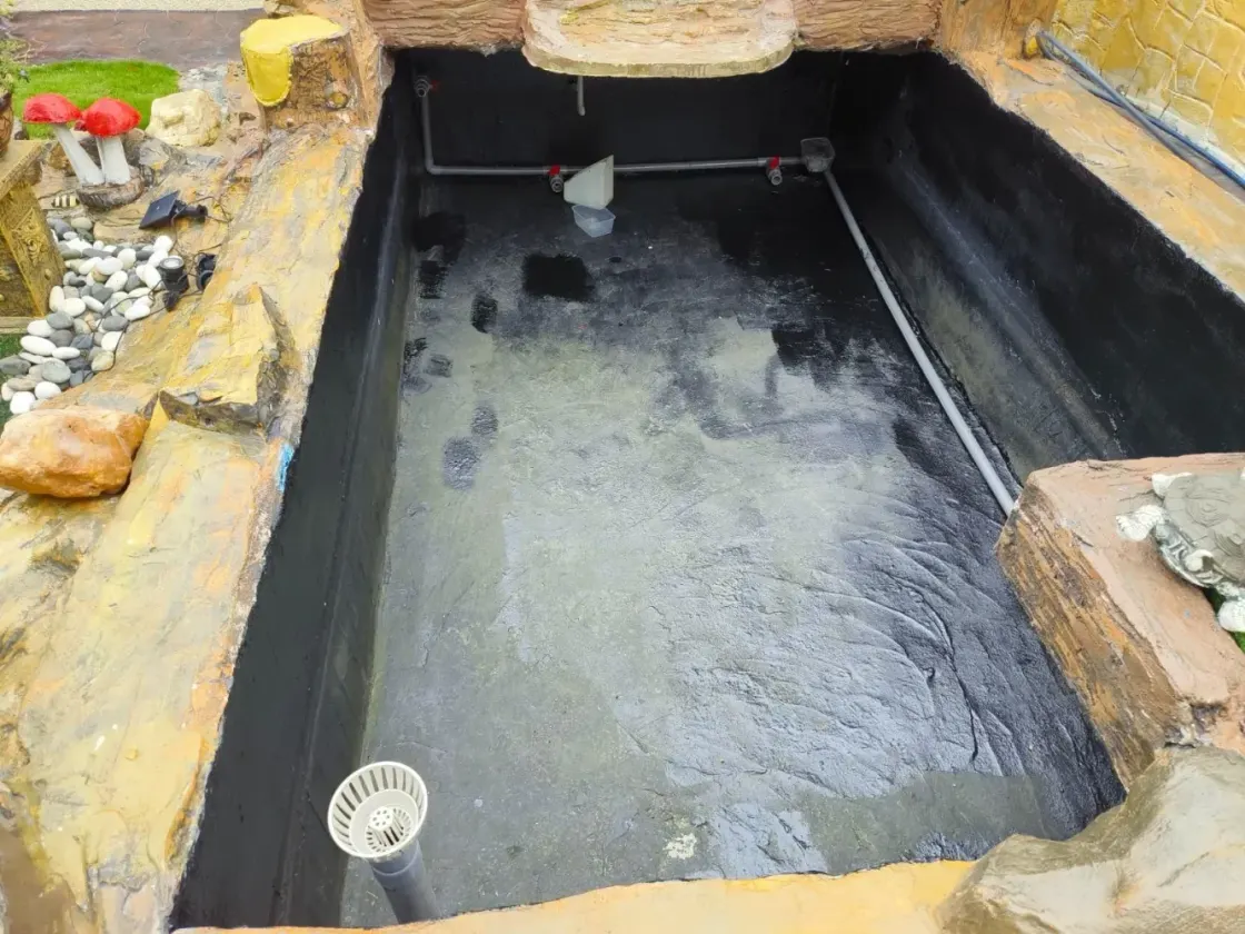 Rubber-lined pond basin with rock edging under construction