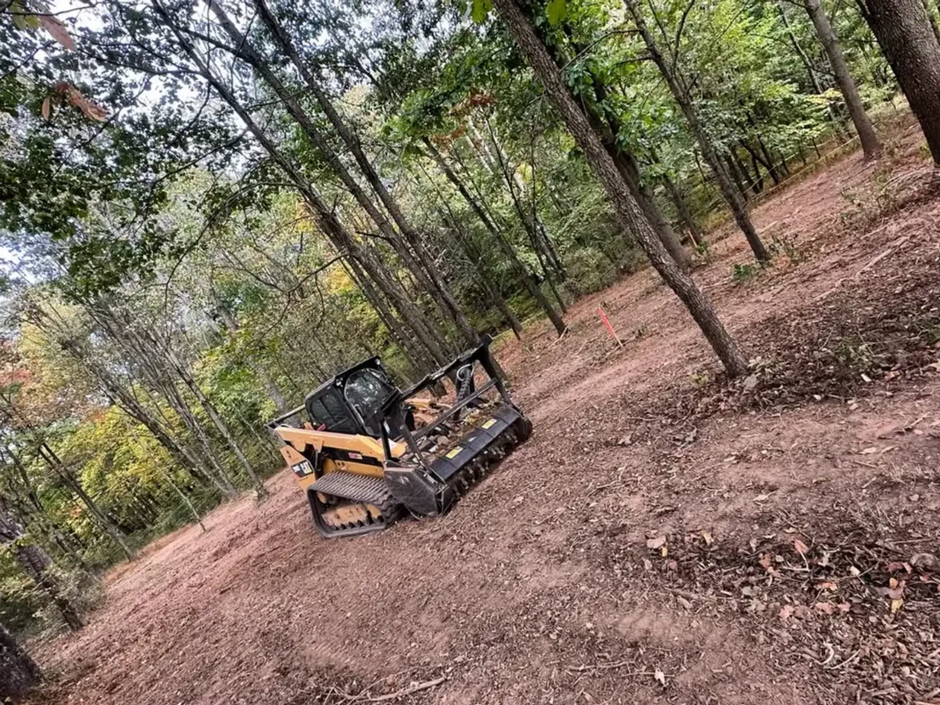 Track loader clearing a wooded slope during lot clearing